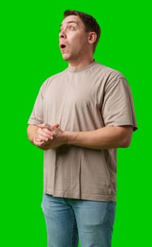 A surprised man stands in front of a bright green screen, expressing shock with his mouth open in studio