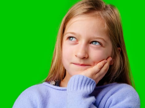 Young girl in a thoughtful pose with a green background in studio