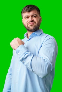 A strong man with fists raised, smiling confidently, on a bright green background in studio