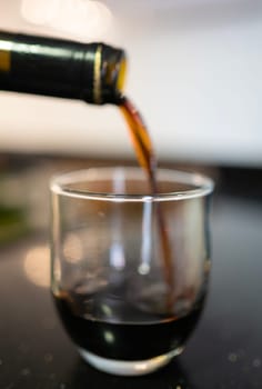 Red wine being poured from a bottle into a glass on a tabletop, creating a moment of anticipation and enjoyment
