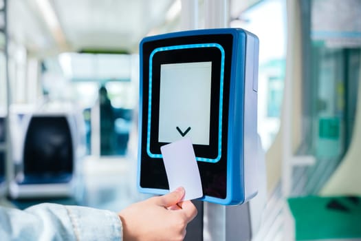Close-up of a hand inserting a ticket into an electronic validation machine inside public transport. The modern digital system allows commuters to verify their travel access efficiently.