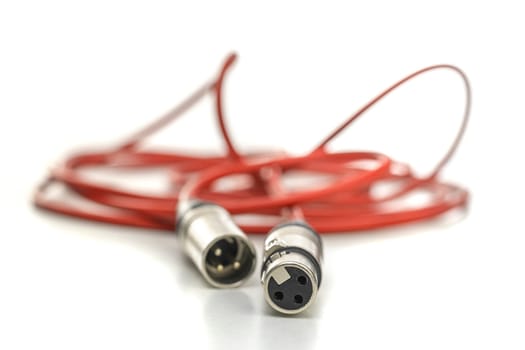 Red xlr cable connecting audio devices on white background