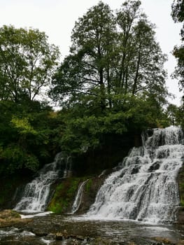 Chervonohorod Dzhuryn waterfall in summer in Ukraine. Travel nature Carpathian Mountains in cloudy cool weather, vertical
