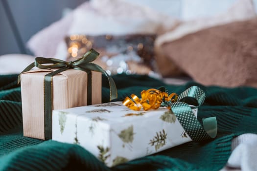 Two presents are sitting on a green blanket. One of them is wrapped in a tree patterned wrapping paper
