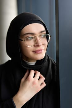 A stunning Muslim businesswoman is captured in a close-up portrait, showcasing her captivating green eyes behind stylish prescription glasses, radiating elegance and confidence.