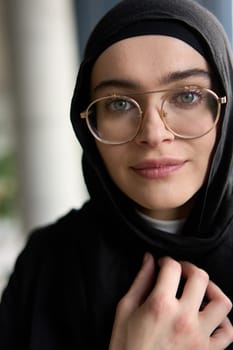 A stunning Muslim businesswoman is captured in a close-up portrait, showcasing her captivating green eyes behind stylish prescription glasses, radiating elegance and confidence.