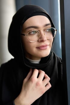 A stunning Muslim businesswoman is captured in a close-up portrait, showcasing her captivating green eyes behind stylish prescription glasses, radiating elegance and confidence.