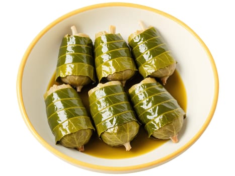 Dolma Turkey Stuffed grape leaves filled with rice, herbs and spices drizzled with lemon garlic sauce in vibrant ceramic bowl,..