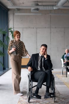 A business director in a wheelchair moves confidently through a modern office alongside his colleague, showcasing teamwork, leadership, and inclusivity in the workplace