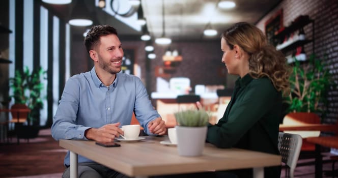 Laughing Male And Female Sitting In Cafe Drinking Coffee And Talking