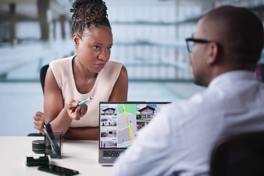 Professional Real Estate Agent Presenting Property Options To Happy Man Using Laptop In Modern Office Setting