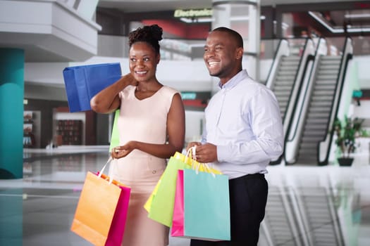 Family With Bags In Shopping Mall. Happy Man And Woman Buying Fashion