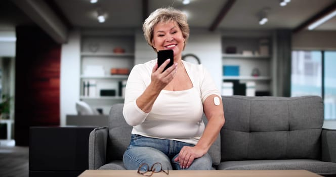 Woman Testing Glucose Level With Continuous Glucose Monitor On Mobile Phone