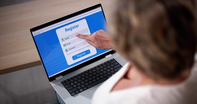 Businesswoman's Hand Filing Online Registration Form On Laptop