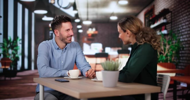 Laughing Male And Female Sitting In Cafe Drinking Coffee And Talking