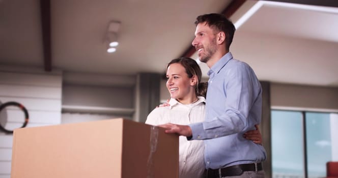 Happy Young Couple Moving Boxes In New Home