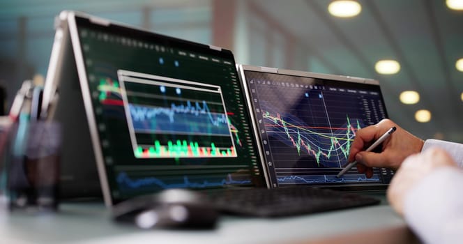 Stock Market Broker Looking At Graphs On Multiple Screens In Office
