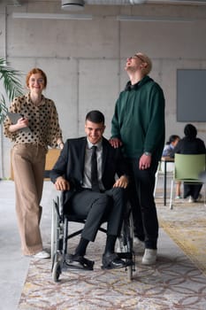 Group cheerful business colleagues, including a businessman in a wheelchair, posing together in a modern office, showcasing teamwork and inclusivity.