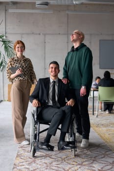 Group cheerful business colleagues, including a businessman in a wheelchair, posing together in a modern office, showcasing teamwork and inclusivity.