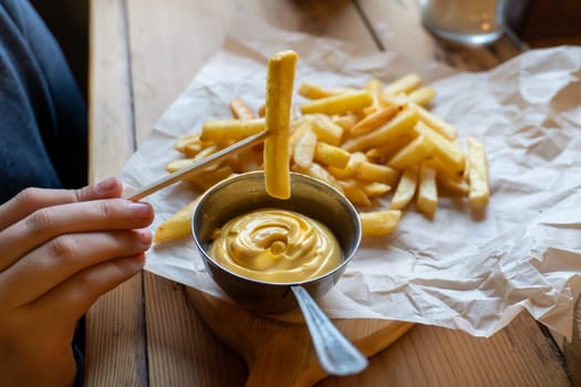 Crispy french fries with creamy cheese dip on rustic table.