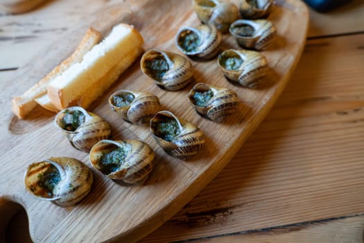 Escargot and bread on wooden tray: french culinary delicacy.