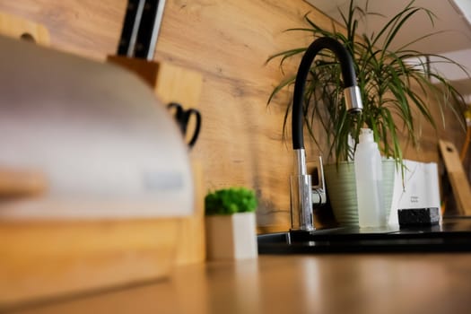 Black sink on the background of a white and wooden modern kitchen with appliances and appliances close-up. High quality photo