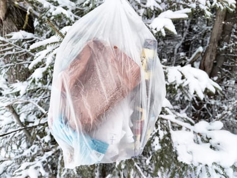 On a winter hike through the snow-covered woods, a plastic garbage bag is found suspended from a tree, highlighting environmental pollution issues.