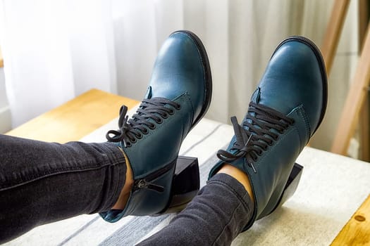 A model poses confidently while displaying fashionable shoes against a minimalistic backdrop with natural light.