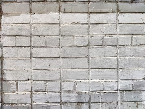 The worn white brick wall exhibits a textured surface with signs of age, presenting a rustic and charming backdrop.