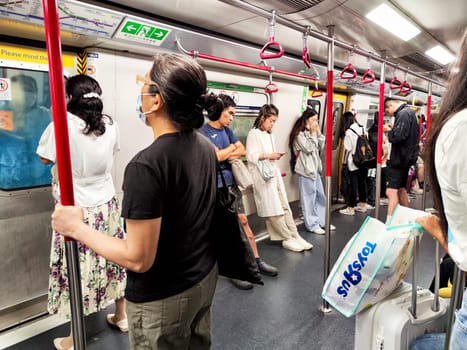 Hong Kong, China - April 09, 2024 - Passengers stand and sit in a busy subway train in Hong Kong, highlighting daily commuting life in the city.