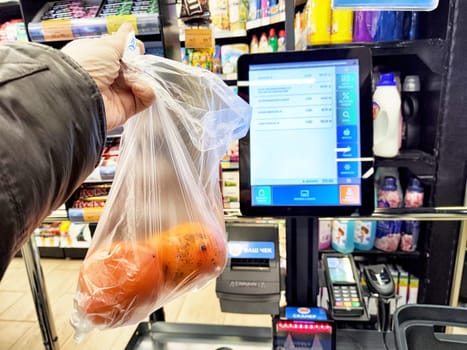 Kirov, Russia - December 11, 2024: Customer at grocery store utilizes self-service checkout to scan and pay for items, facilitating a quick shopping experience.