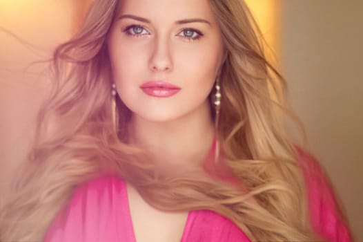 Woman with blue eyes and long, voluminous blonde hair styled in soft curls, wearing pink dress and elegant earrings, dreamy and feminine look idea