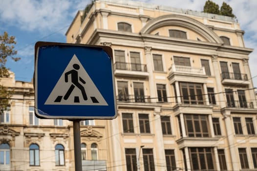 A street sign in front of a building. High quality photo. pedestrian crossing sign in the city with a building in the background. road sign in the city and a large residential building behind it