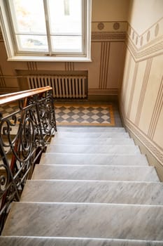 marble staircase indoors. luxurious staircase with light steps and beautiful lacquered railings. which are made of wood and iron