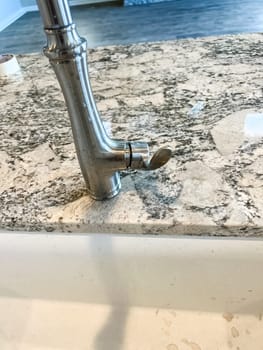 Castle Rock, Colorado, USA-February 11, 2023-Close-up view of a modern kitchen faucet mounted on a granite countertop in a newly constructed home. The faucet design features a sleek finish and is part of a stylish kitchen sink setup.