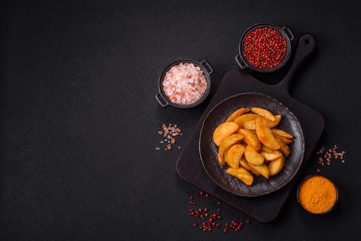 Baked potato wedges with cheese and herbs on a dark background. Homemade organic vegetable vegan vegetarian potato wedges