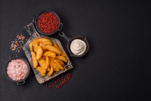 Baked potato wedges with cheese and herbs on a dark background. Homemade organic vegetable vegan vegetarian potato wedges
