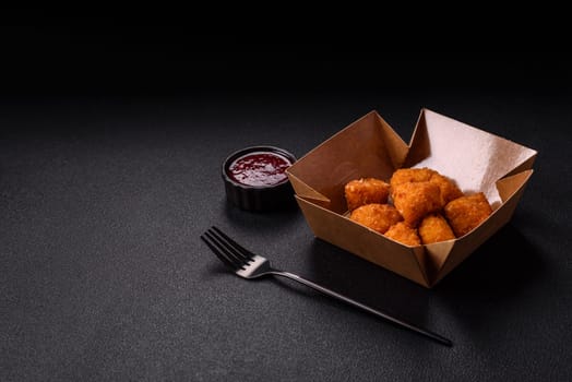 Brie cheese or camembert fries in breading, fast food, takeaway on a dark concrete background