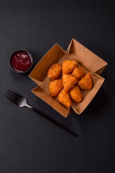 Brie cheese or camembert fries in breading, fast food, takeaway on a dark concrete background