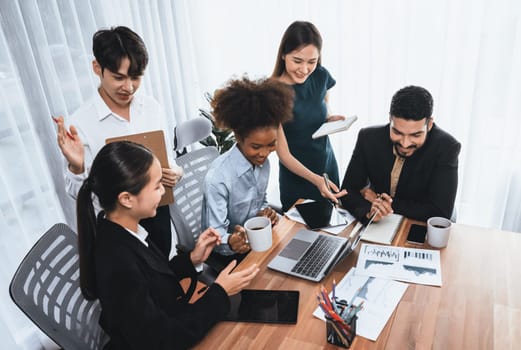 Multiracial analyst team use BI dashboard data to analyze financial report on meeting table. Group of diverse business people utilize data analysis by FIntech for success business marketing. Concord