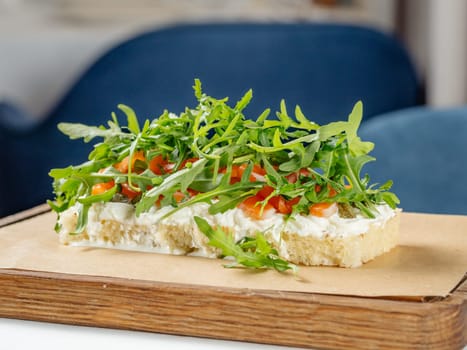 Tasty bruschetta with salmon and arugula on restaurant table in interior