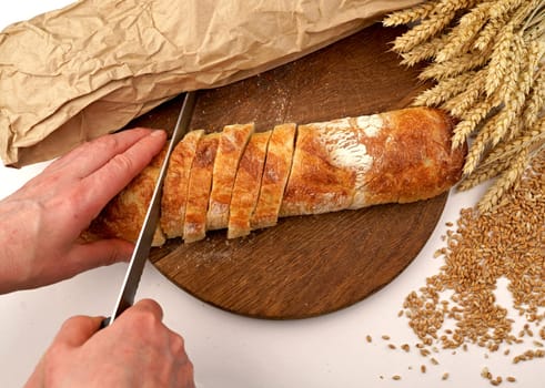 woman cutting fresh crispy wheat bread on a wooden board