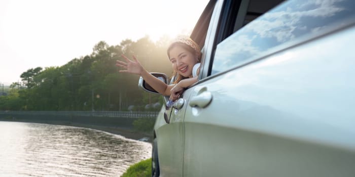 Smiling female driving vehicle on the road on a bright day. Sticking her head out the windshield.