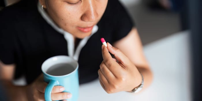 Close up woman holding pill in hand with water feeling sick. female going to take painkiller from headache, painkiller, healthcare, medicine, treatment, therapy, patient, disease illness concept.