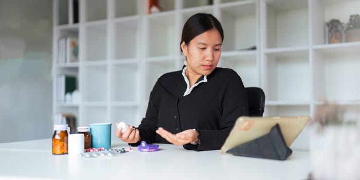 Health care asian young woman using tablet for search prescription on bottle medicine, pill label text about information online, instruction side effects, pharmacy medicament concept.