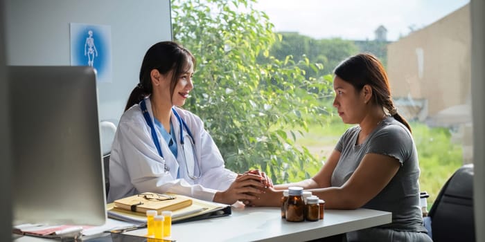 Doctor giving hope. Close up shot of young female physician leaning forward to smiling lady patient holding her hand in palms. Woman caretaker in white coat supporting encouraging old person.