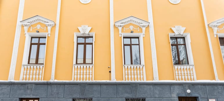 Elegant classical windows decorated with stucco ornaments on beige antique facades. Vintage classic architecture.