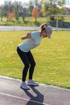 A young beautiful woman in sportswear plays sports at a local stadium. Exercise, jog and exercise at the beginning of the day. Healthy and active lifestyle.