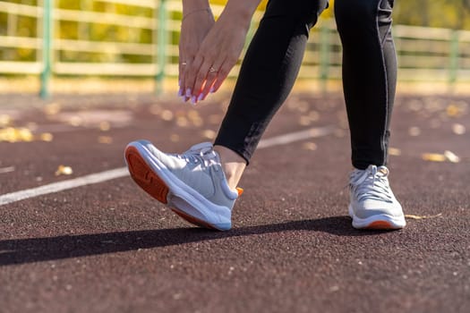 A young beautiful woman in sportswear plays sports at a local stadium. Exercise, jog and exercise at the beginning of the day. Healthy and active lifestyle.