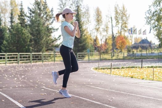 A young beautiful woman in sportswear plays sports at a local stadium. Exercise, jog and exercise at the beginning of the day. Healthy and active lifestyle.